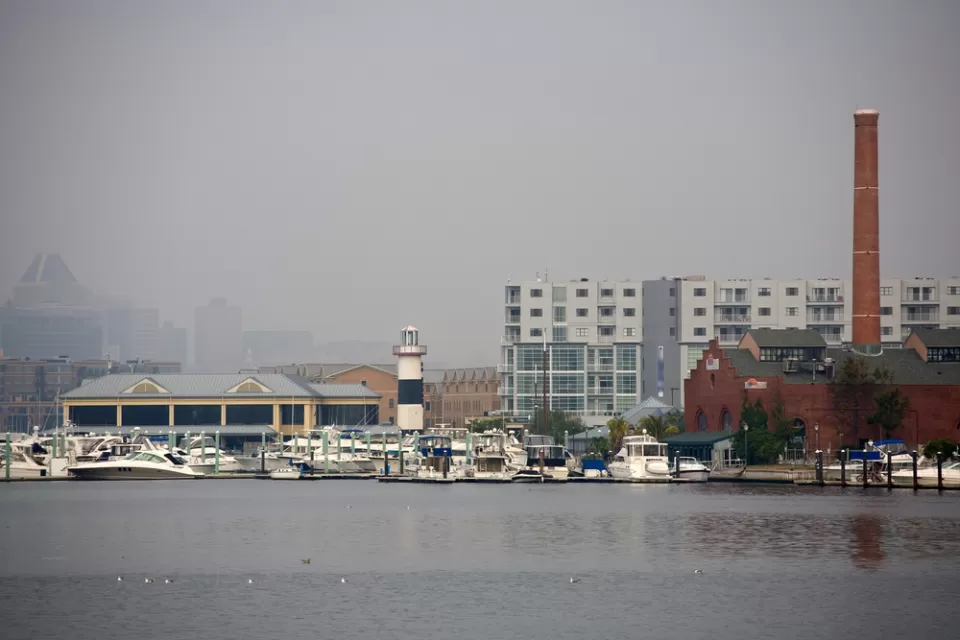 The city of Baltimore's Inner Harbor blanketed in fog, as seen from the water.